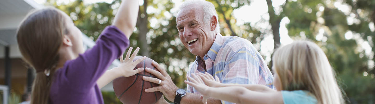 el abuelo juega al baloncesto con dos niñas
