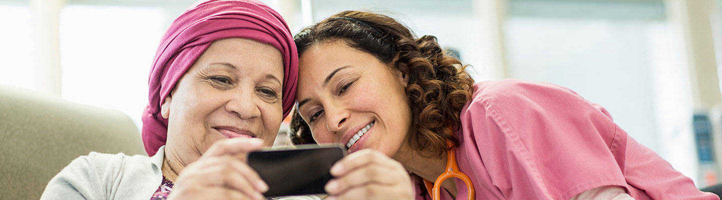 Mujer cáncer con diadema sonriendo al teléfono con un cuidador