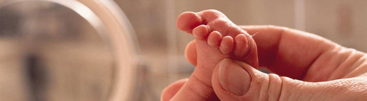 Cerrar en la mano sosteniendo la pierna de un bebé prematuro