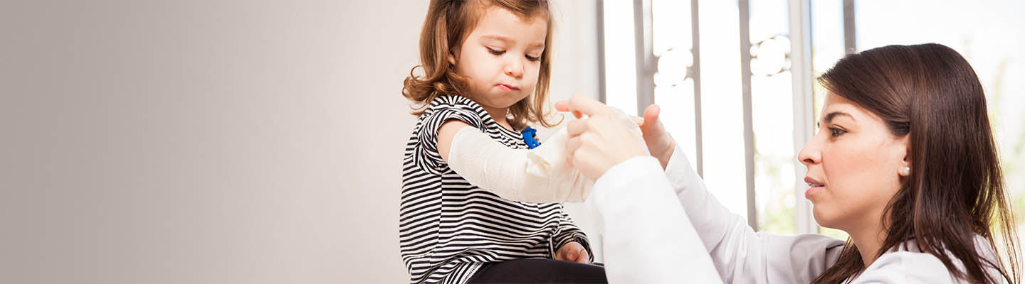 Un pediatra aplica un yeso a una niña.
