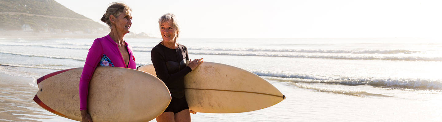 dos, mujeres mayores, proceso de llevar, tablas de surf, en la playa