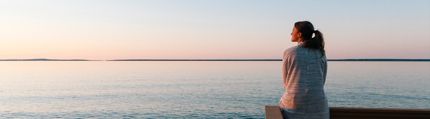 Mujer sentada en el muelle mirando al océano