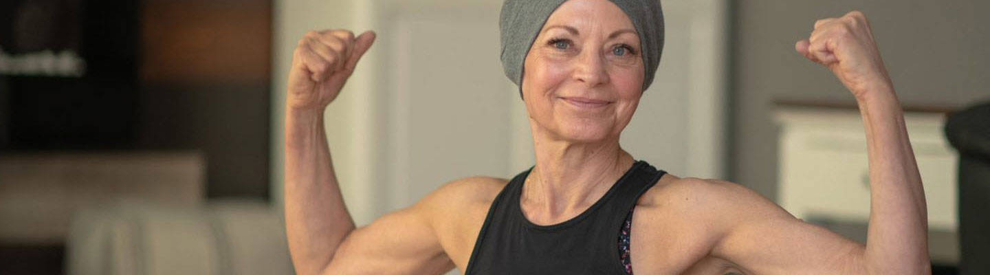 Mujer con cáncer flexionando en estudio de yoga
