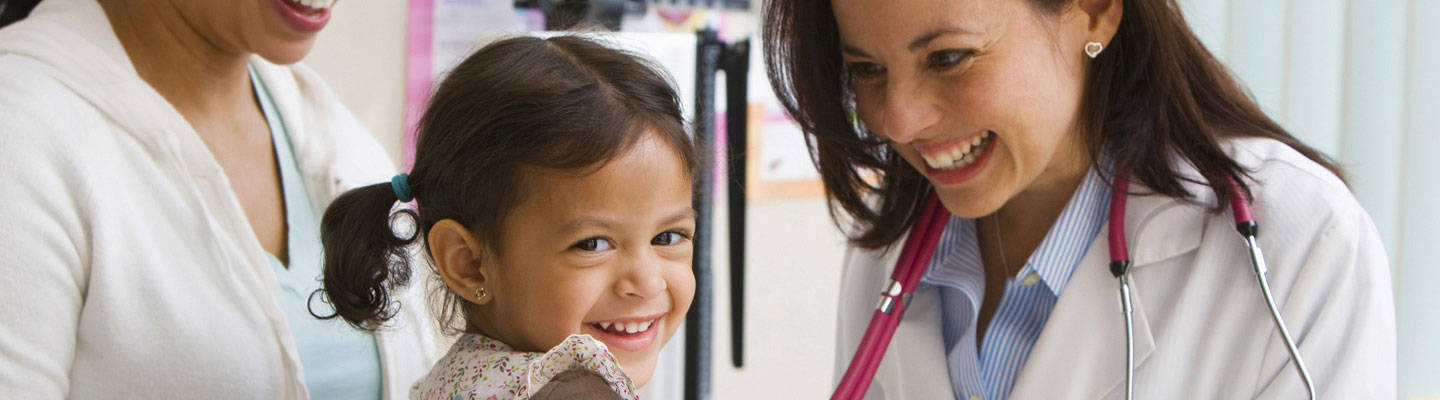 Una mujer pediatra haciendo sonreír a una niña