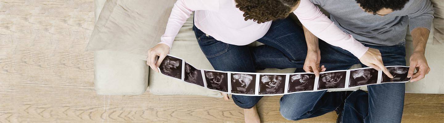 mujer embarazada y su pareja miran las imágenes de una ecografía
